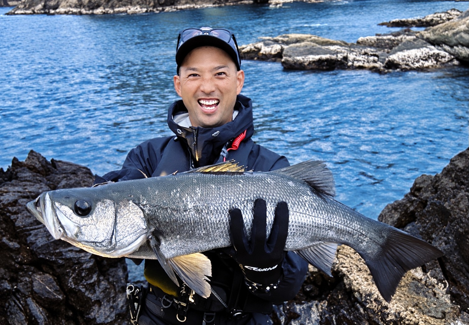 釣り上げた魚を手に笑顔を見せる宇佐川さん